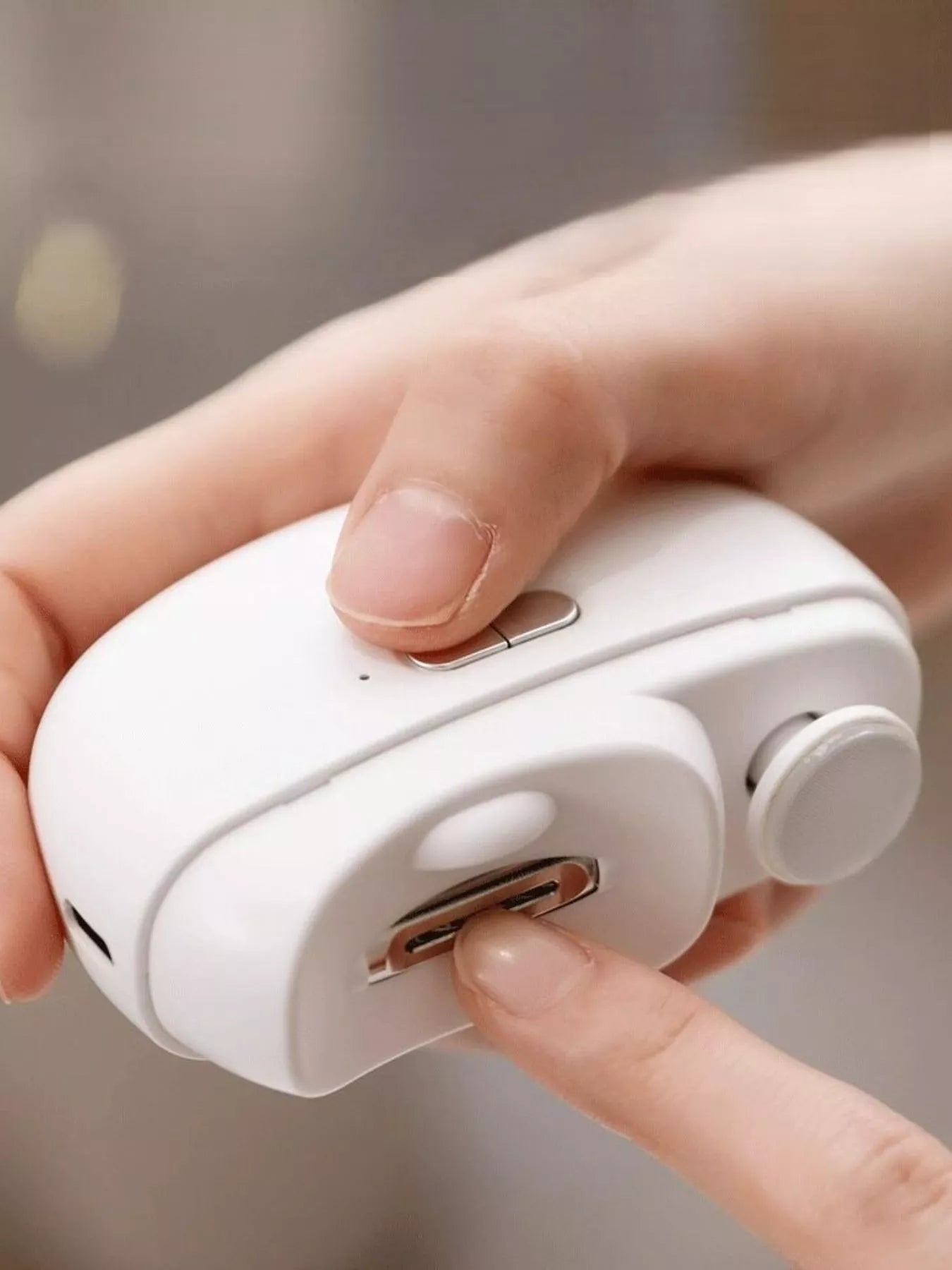 White electric nail buffer held in hand with side control slot