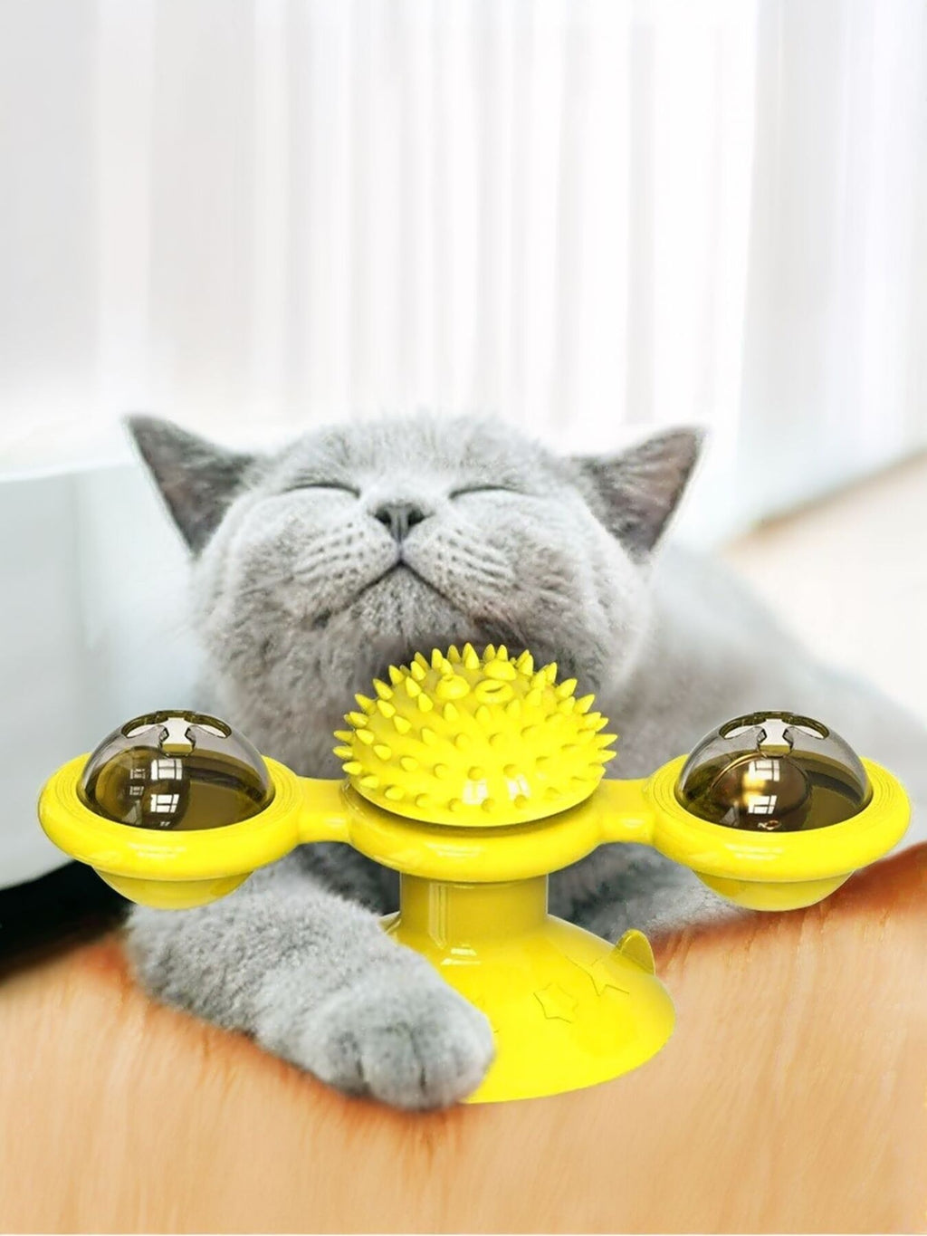 Yellow rotating cat toy with three suction cup pods and spiky center wheel