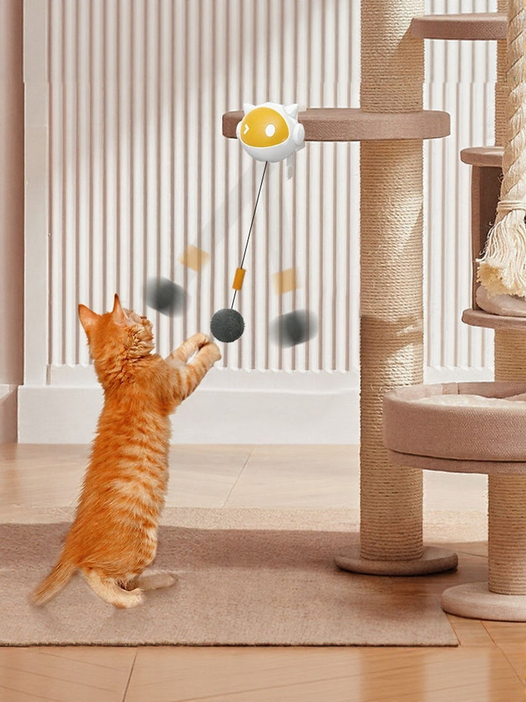Interactive hanging cat teaser toy: yellow egg ball with strings and two gray pom-poms