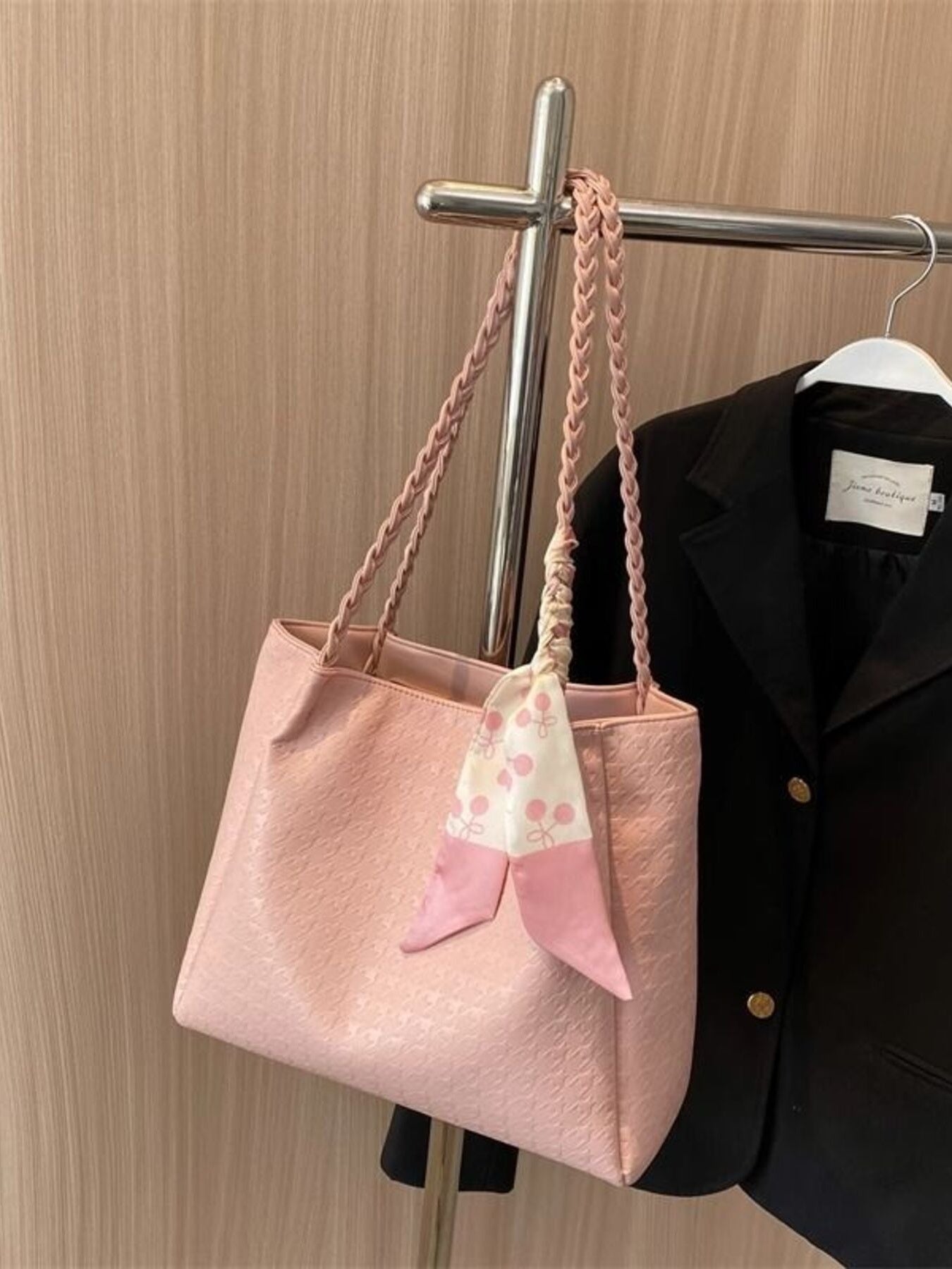 Blush pink braided handle tote bag hanging on a rack, with ribbon tie