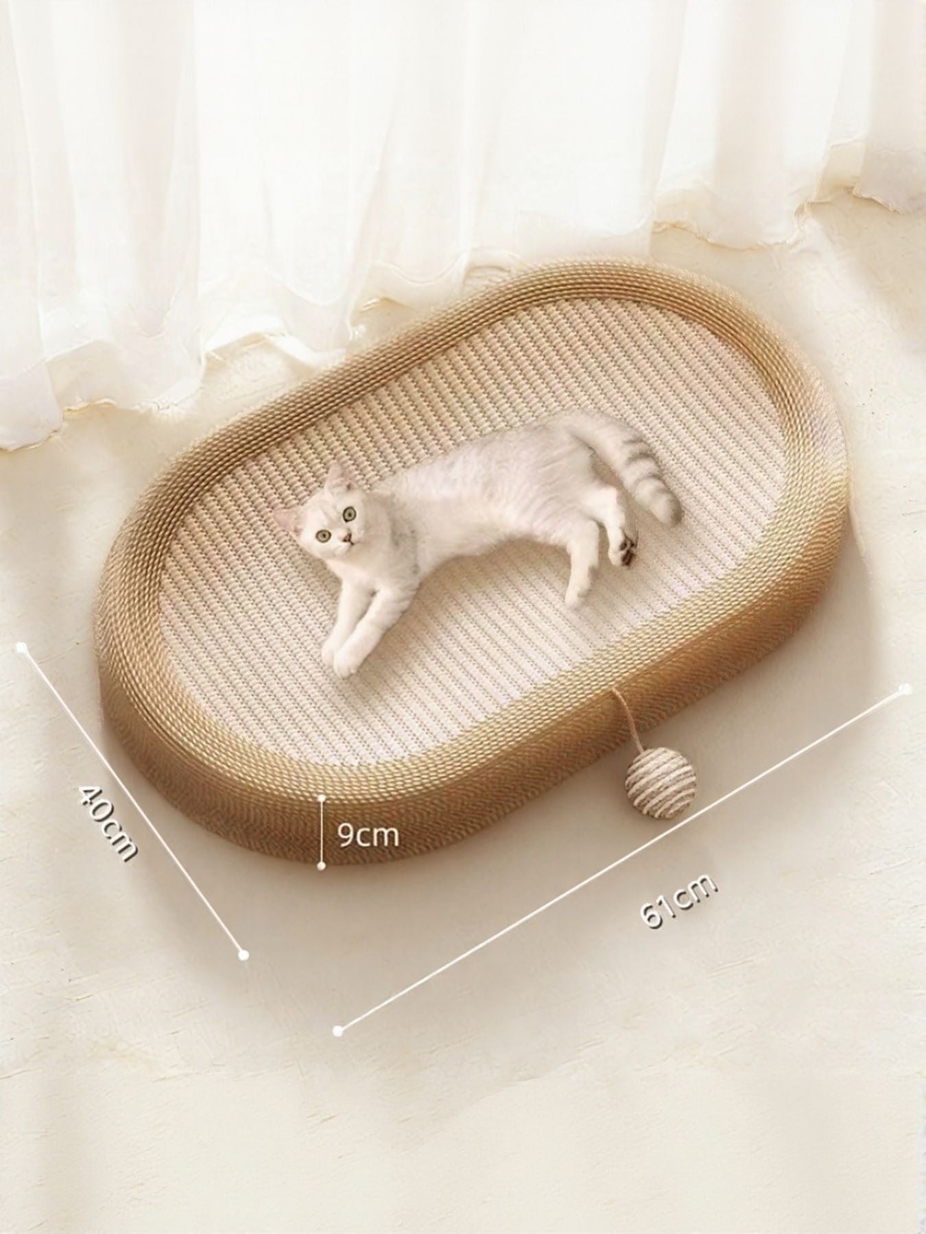 Beige oval woven cat scratching bed with cat inside and rope toy at the side