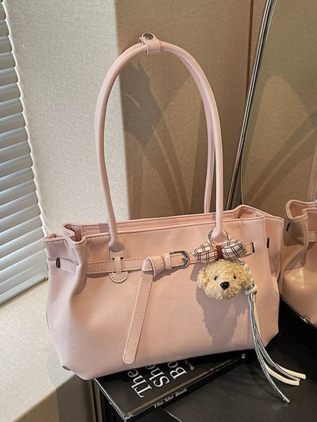 Blush pink leather shoulder bag with dog charm, top handle, front buckle details