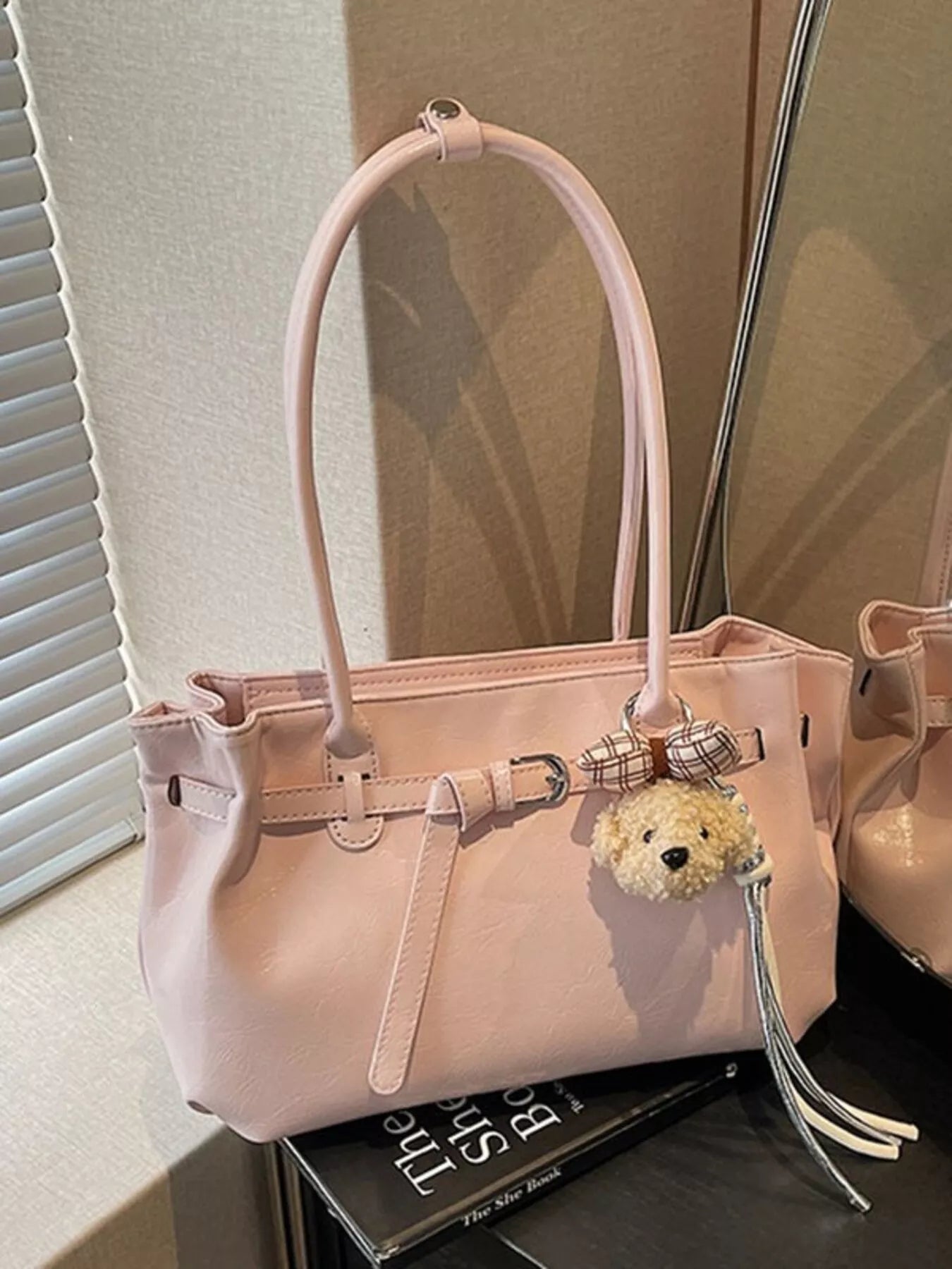 Blush pink leather shoulder bag with dog charm, top handle, front buckle details