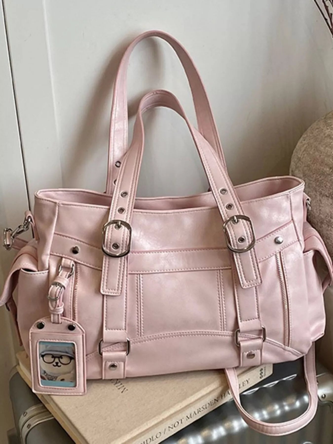 Pink buckle-detail shoulder bag with front pockets and hanging card-style charm