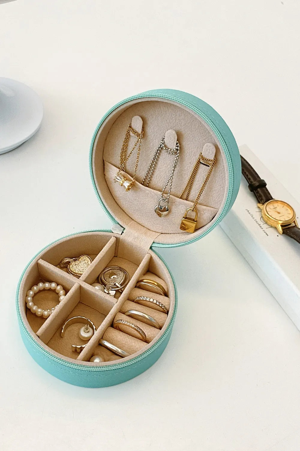 Turquoise PU leather jewelry storage box, open with jewelry arranged in ring and necklace holders