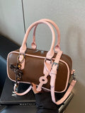 Barrel Crossbody Bag mit Schlüsselanhänger, braunem Korpus und rosafarbenen Riemen
