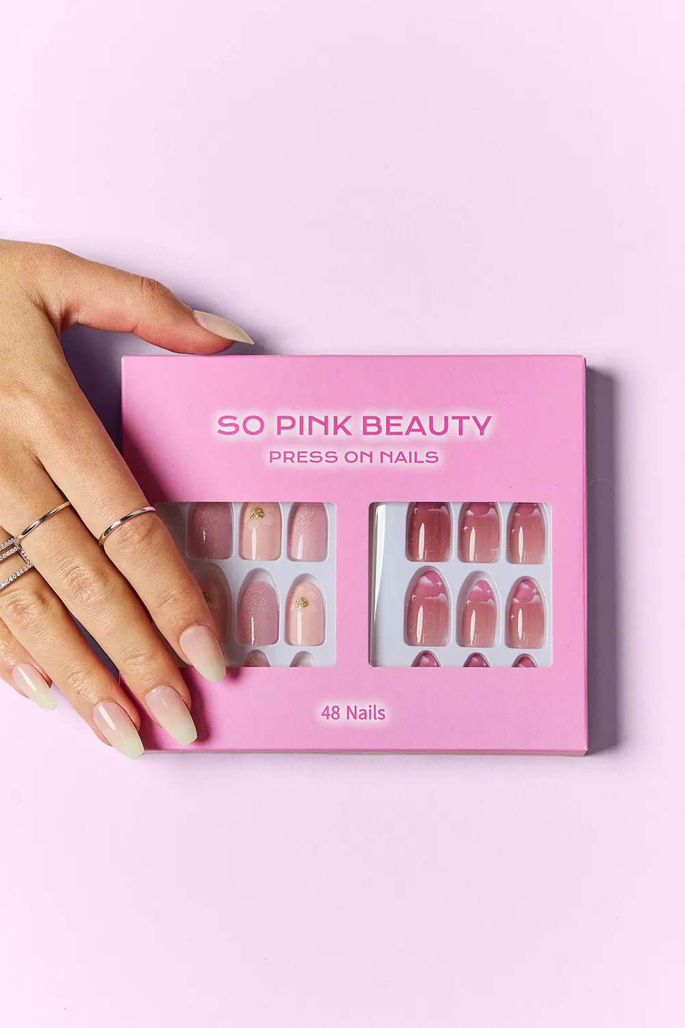 SO PINK BEAUTY press-on nails in pink box; hand displays pastel and red patterned designs