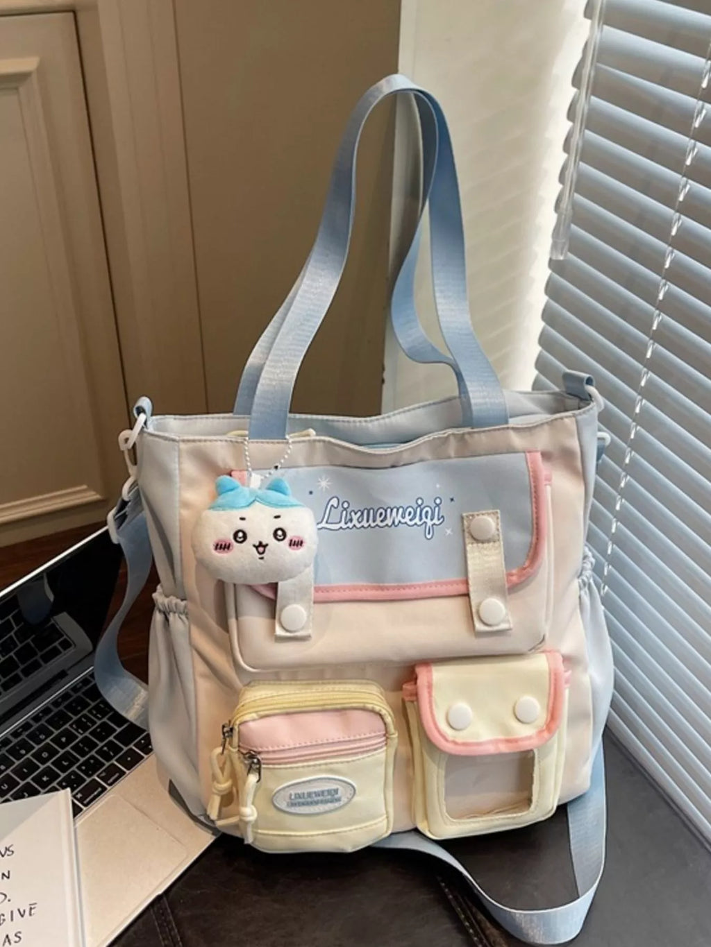 Multi-pocket shoulder bag with pastel blue straps, plush charm, front organizer pockets