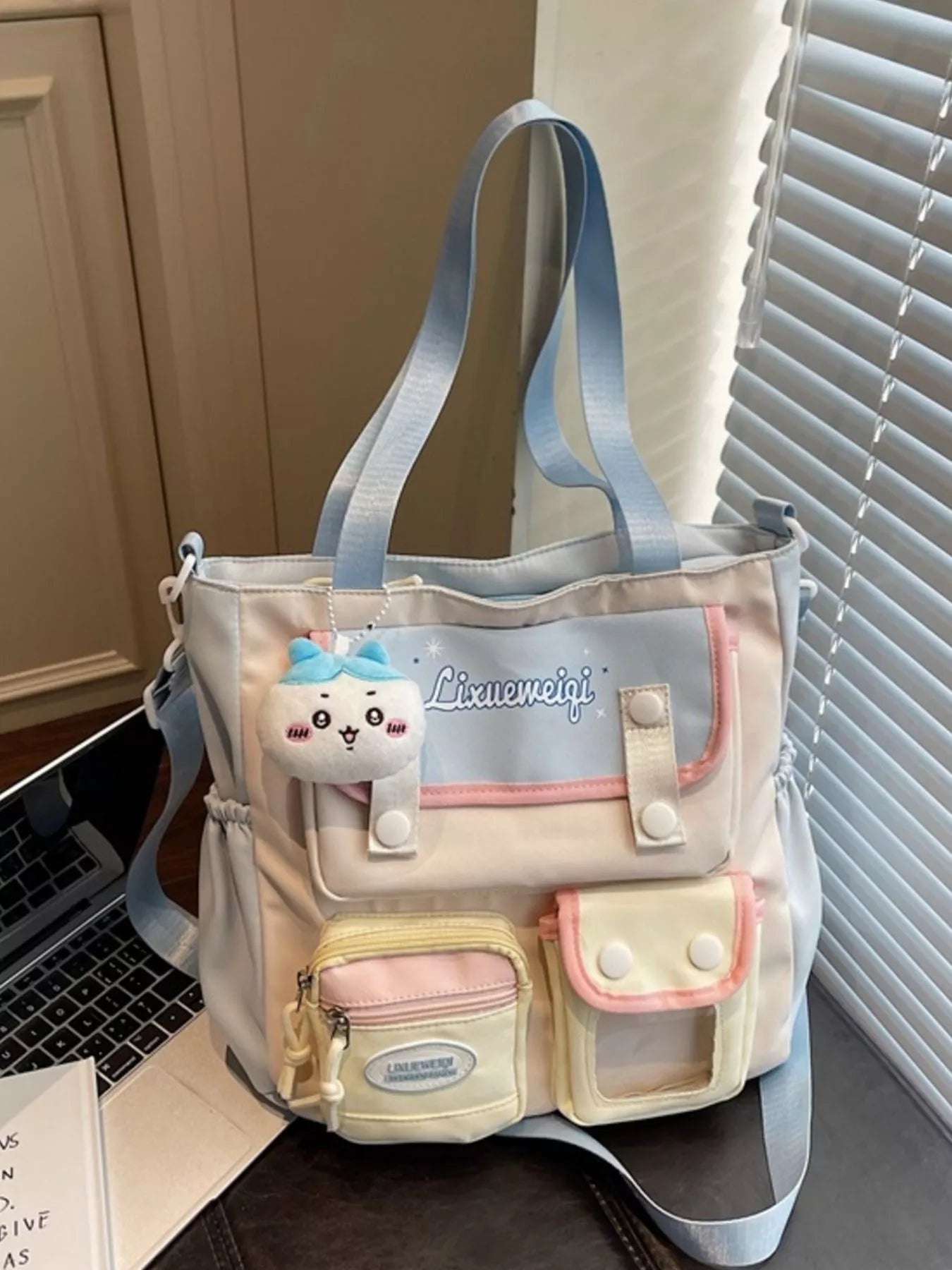 Multi-pocket shoulder bag with pastel blue straps, plush charm, front organizer pockets