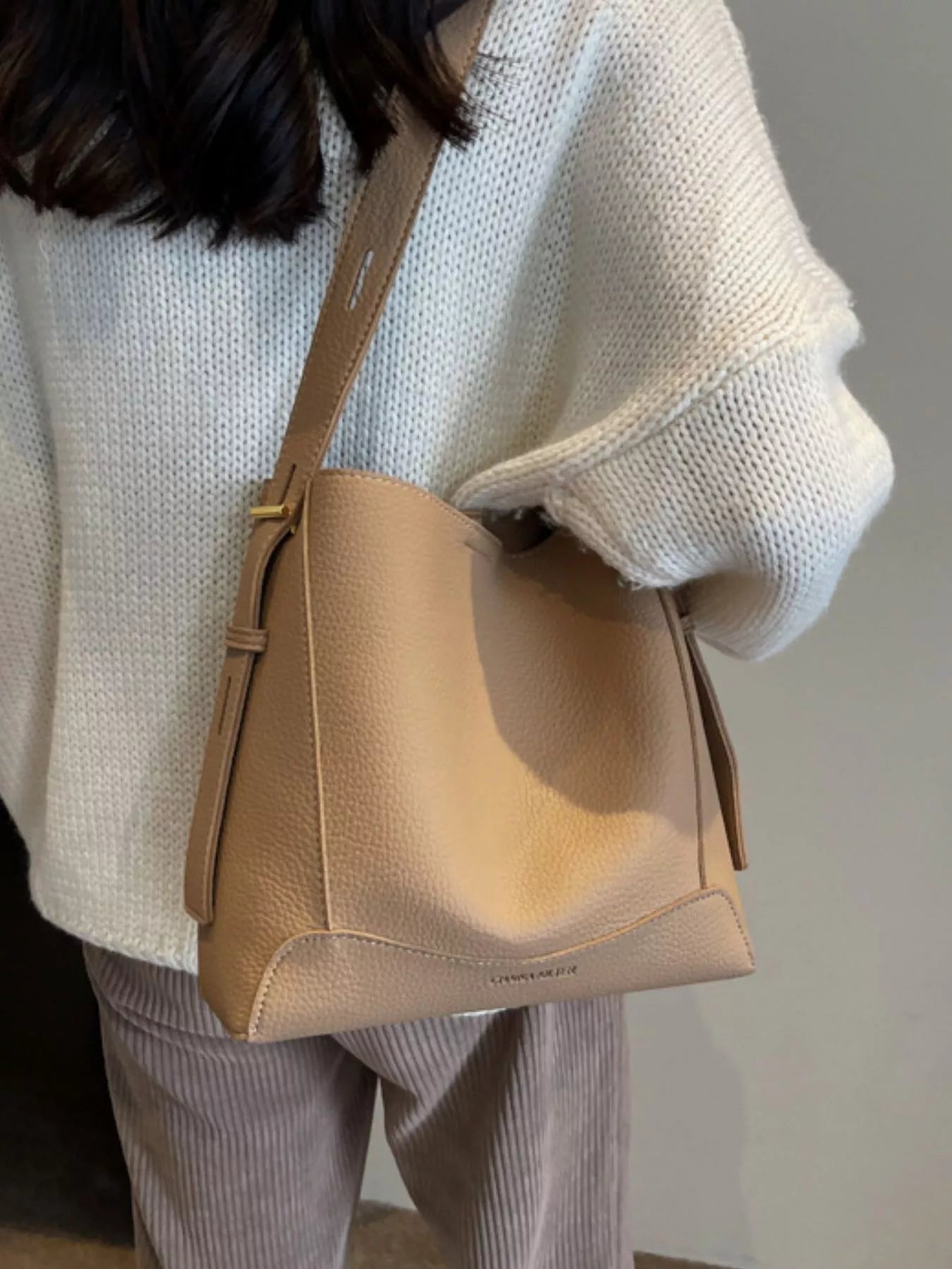 Khaki leather crossbody bag with adjustable strap, zip-top, and front panel seam