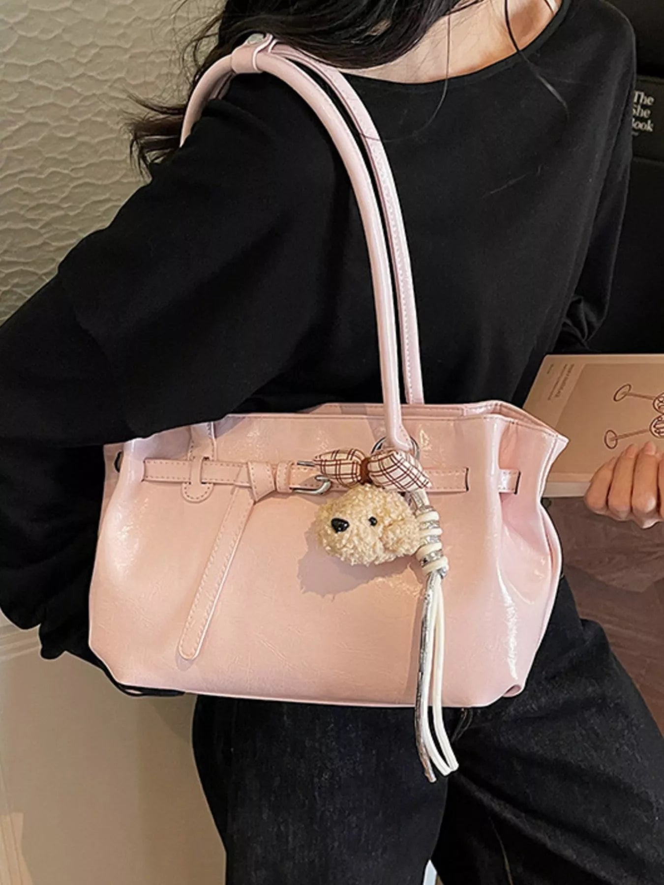 Blush pink leather shoulder bag with dog charm keyring and silver tassel, worn on arm
