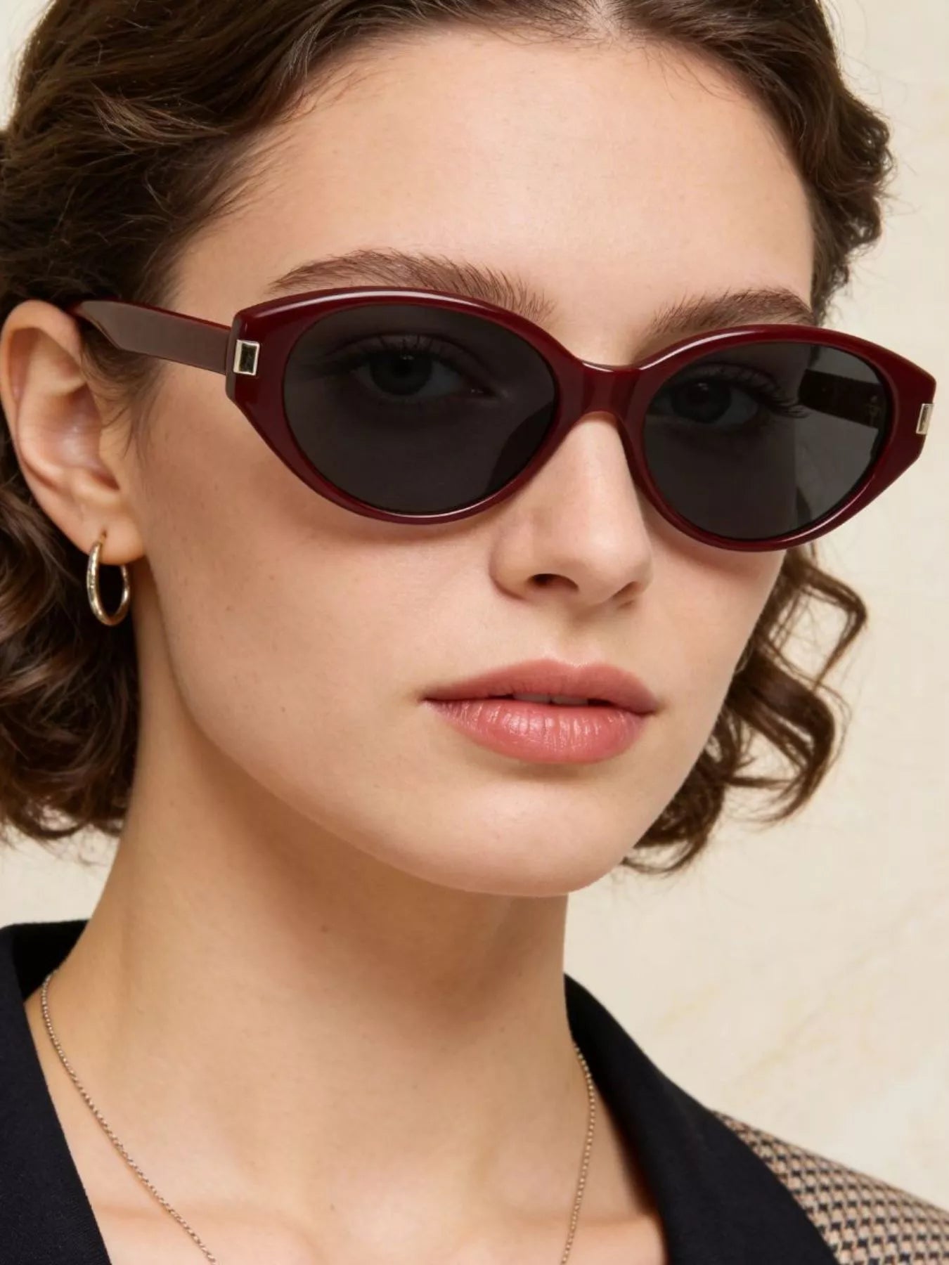 Cat-eye sunglasses with dark red frame, black lenses, and square metal hinge
