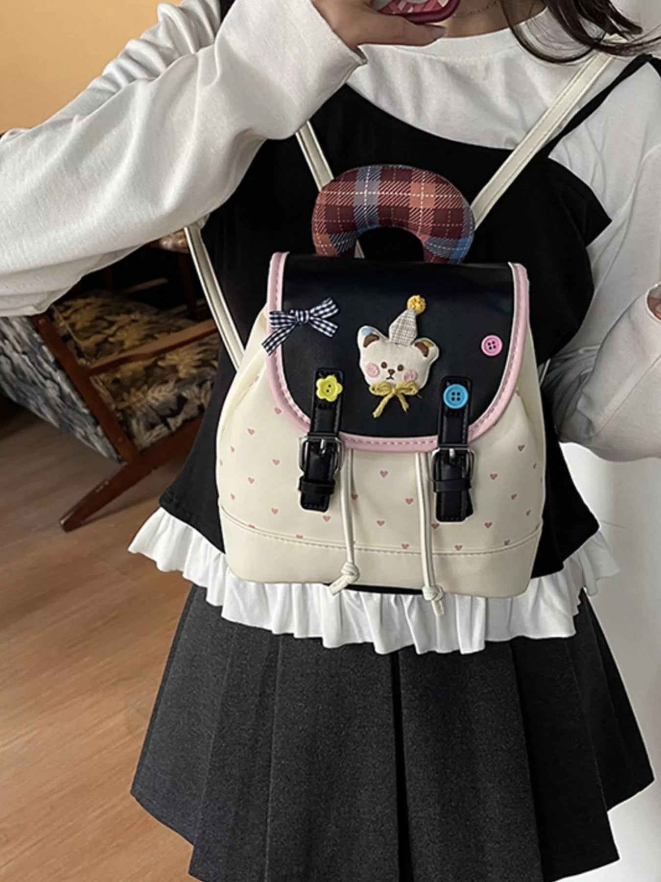 Beige backpack worn on a child: front bear appliqué, plaid handle, pink edging